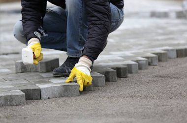Paving stone worker is putting down pavers during a construction of a city street.